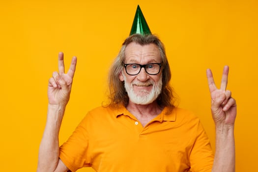Senior grey-haired man fun birthday cap on the head isolated background photo