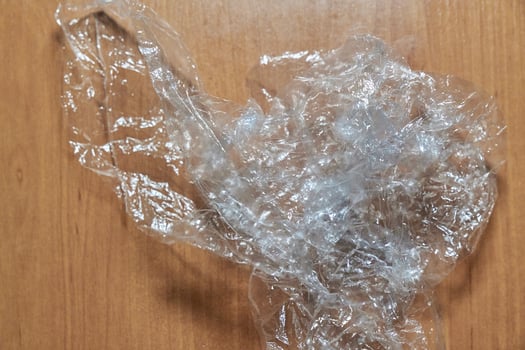 Crumpled transparent film on a wooden surface. Plastic trash. photo