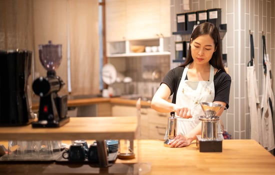 Female hand mash coffee bean in coffee grinder on wooden table. photo