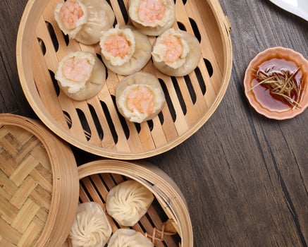 Prawn shrimp shaomai Xiao long bao dim sum dumpling chicken prawn fish seafood vegetable in bamboo steamer sauce chopsticks on rustic background photo