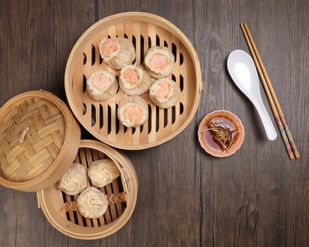 Prawn shrimp shaomai Xiao long bao dim sum dumpling chicken prawn fish seafood vegetable in bamboo steamer sauce chopsticks soup spoon on rustic background photo