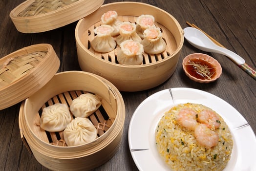 Prawn shrimp shaomai Xiao long bao dim sum dumpling chicken prawn fish seafood vegetable in bamboo steamer fried rice on plate sauce chopsticks soup spoon over rustic background photo