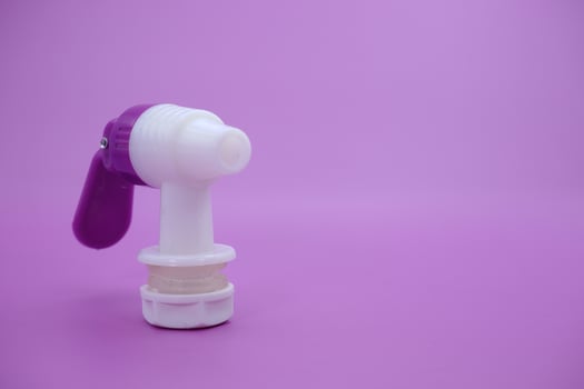 closed faucet isolated purple background. the faucet is white with a purple lid photo