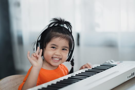 Asian cute girl wearing headphone learning online piano music with teacher by mobile phone or tablet. The idea of activities for the child at home during quarantine. Music learning study concept. photo