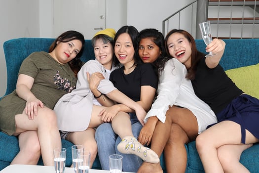 Young Asian woman group talk gossip chat sing drink cheers party fun enjoy funny faces expression on blue living room sofa photo