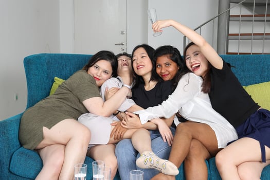 Young Asian woman group talk gossip chat sing drink cheers party fun enjoy funny faces expression on blue living room sofa photo
