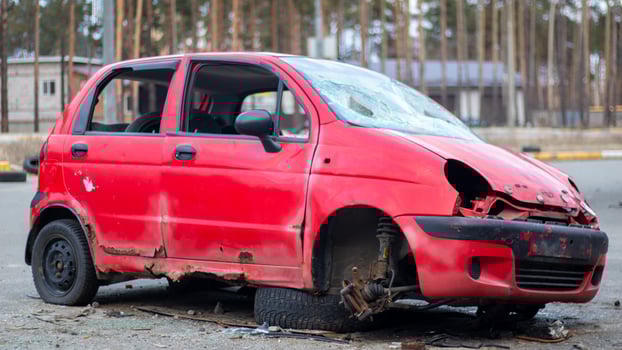 Rusty and broken red abandoned car on the city street. Abandoned old car accident outdoors. Old abandoned rusty car without wheels on the side of the road. photo