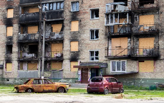 The car that burned down after the bombing of the city stands in the courtyard of a destroyed house. War between Russia and Ukraine. Fragments of a car after artillery shelling. photo