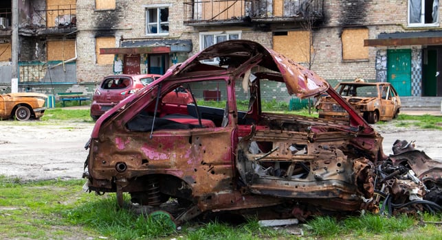 The car that burned down after the bombing of the city stands in the courtyard of a destroyed house. War between Russia and Ukraine. Fragments of a car after artillery shelling. photo