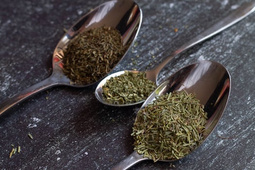 Spoons with spices and herbs on a black background. Food and cuisine ingredients. photo