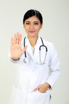 Young Asian female doctor wearing apron stethoscope stop hand sing photo