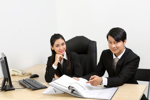 Young Asian male female wearing suit sitting at office desk thinking meeting disucsing sign document agreement photo