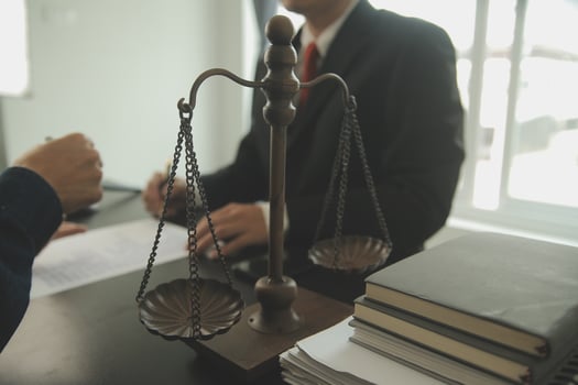 Business and lawyers discussing contract papers with brass scale on desk in office. Law, legal services, advice, justice and law concept picture with film grain effect photo