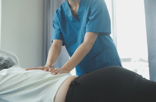Doctor or nurse or physiotherapist caregiver exercise with senior woman at clinic or nursing home photo