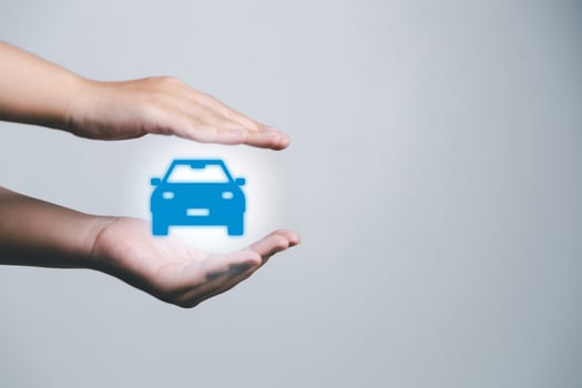Business woman's hand protecting blue icon car on desk. Planning to manage transportation finance costs. Concept of car insurance business, saving buy - sale with tax and loan for new car. photo