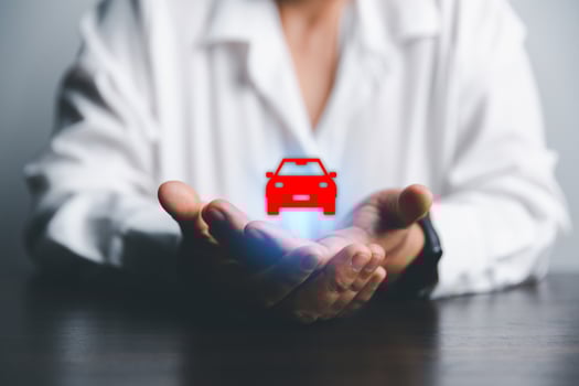 Business woman's hand protecting red icon car on desk. Planning to manage transportation finance costs. Concept of car insurance business, saving buy - sale with tax and loan for new car. photo