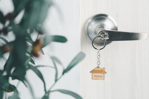 close up key on the door with morning light, personal loan concept. House model and key in house door. Real estate agent offer house, property insurance and security, affordable housing concepts. photo