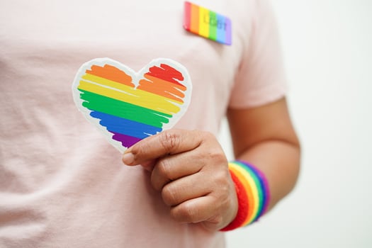 Asian woman holding red heart with rainbow flag, LGBT symbol rights and gender equality, LGBT Pride Month in June. photo