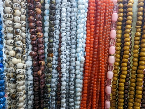 Muslim prayer chaplet market close up shot. Colorful plastic rosaries close up shot in the market. Religious beads with colorful strings. Beautiful Muslim prayer beads close up view. photo