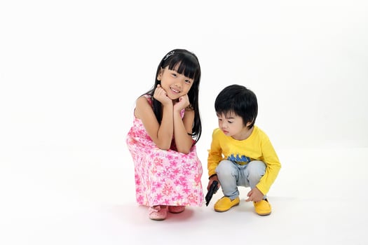 South East Asian young girl boy child brother sister siblings squat siting playing happy posing talking hands on white background photo