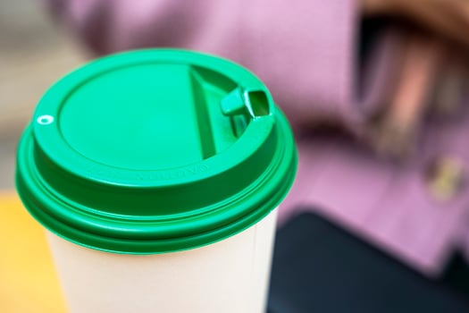 close-up of hot coffee in a paper cup on a table in an outdoor cafe photo