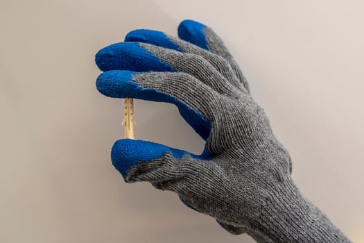 A worker 's hand in a protective glove holds a plastic dowel pin photo