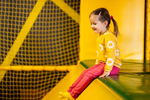Baby girl kid slide at yellow playground park. Child in active entertaiments. photo