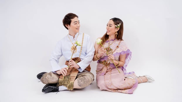 Asian couple in traditional thai costume holding lotus and looking at each other isolated on white background, Thailand traditional culture photo