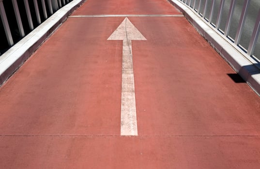 White arrow pointing forward on a red street photo