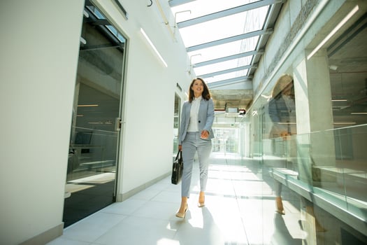 Pretty young business woman walking with briefcase in the office hallway photo
