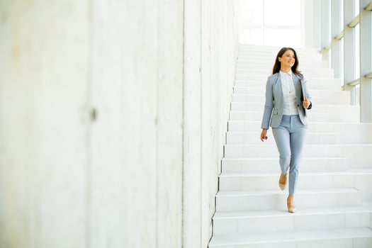 Young business woman walking down the stairs and holding laptop photo