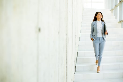 Young business woman walking down the stairs and holding laptop photo