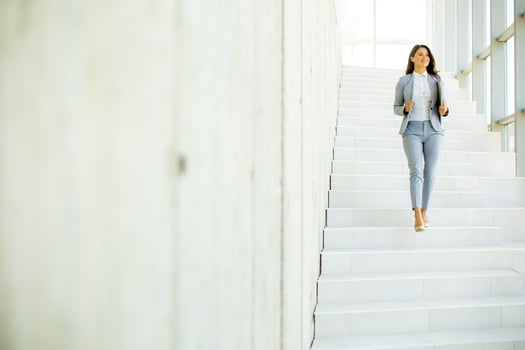 Young business woman walking down the stairs and holding laptop photo