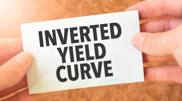 INVERTED YIELD CURVE word inscription on white card paper sheet in hands of a businessman. recap concept. red and white paper photo