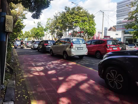 Surakarta, Indonesia - April 27, 2023. Vehicle traffic with some motorcycles and Cars on road with buildings background in big city photo