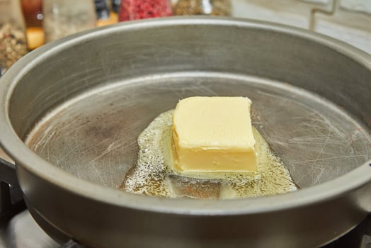 Butter is melted in frying pan over low heat photo