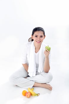 Beautiful young south east Asian Chinese healthy workout exercise sit on floor holding green apple look at camera on white background photo