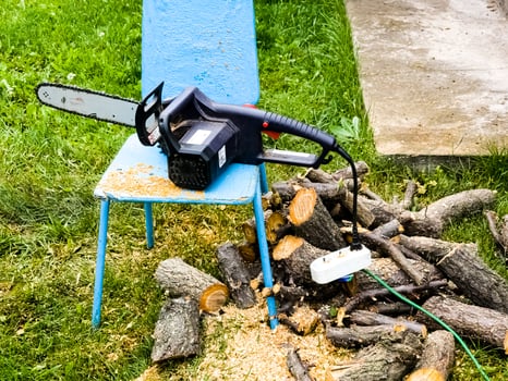 Electric chain saw and sawn wood during seasonal working in the garden and cutting trees for firewood. photo