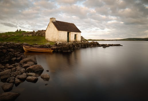 Beautiful morning lakeside scene of fisherman's hut and wooden boat reflected in lake at Screebe, connemara national Park in County Galway, Ireland photo