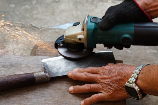 Close up mechanic hands use electric grinders to sharpen iron knife. Concept, traditional style of fixing tool, maintenance tools for cooking, make knife sharp ,not dull for long live using. photo