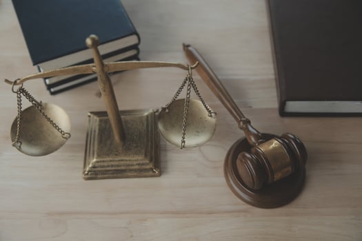 Justice and law concept.Male judge in a courtroom with the gavel, working with, computer and docking keyboard, eyeglasses, on table in morning light photo
