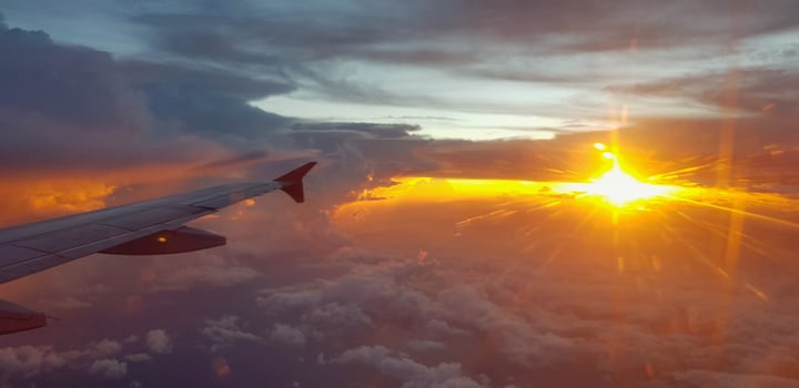 Silhouette of aircraft or airplane wing on dark sky with sunset light flare background. Transportation, Travel and Beauty of Nature concept photo