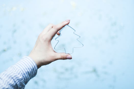 A hand holds a Christmas tree shaped cookie cutter. Bake Christmas cookies photo