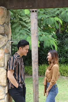 Young Asian Malay man woman outdoor green park walk talk discuss mingle under umbrella photo