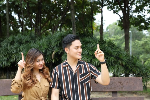 Young Asian Malay man woman outdoor green park walk talk discuss mingle under umbrella photo