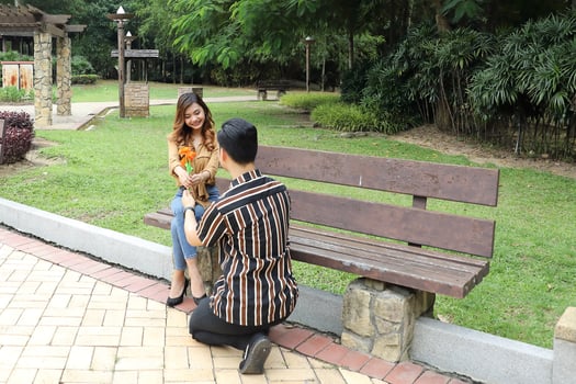 Young Asian Malay man woman outdoor green park walk talk discuss mingle under umbrella photo