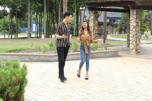 Young Asian Malay man woman couple outdoor green park walk talk discuss mingle photo