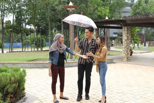 Young Asian Malay man woman outdoor green park walk talk discuss mingle under umbrella photo