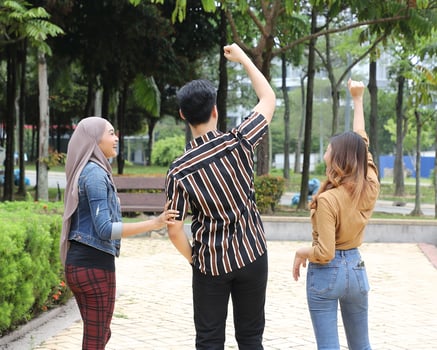 Young Asian Malay man woman outdoor green park walk talk discuss mingle joy arm in air photo
