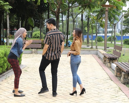 Young Asian Malay man woman outdoor green park walk talk discuss mingle sign show photo